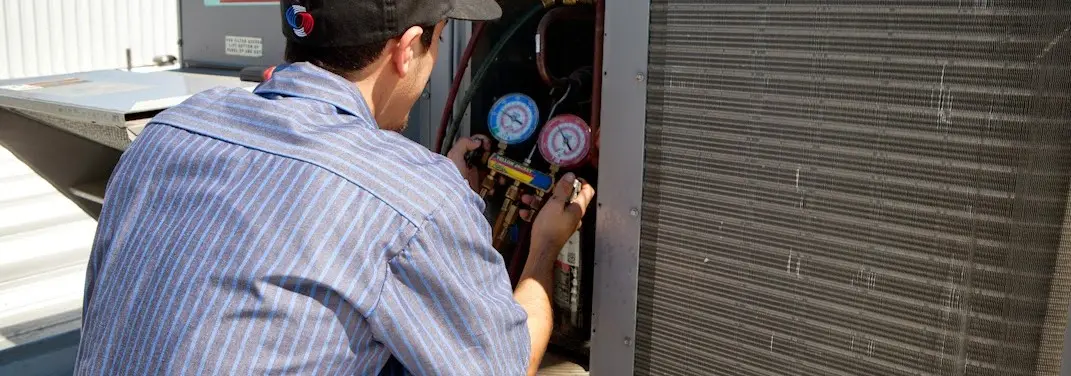 HVAC technician servicing a condenser unit in Capitol View
